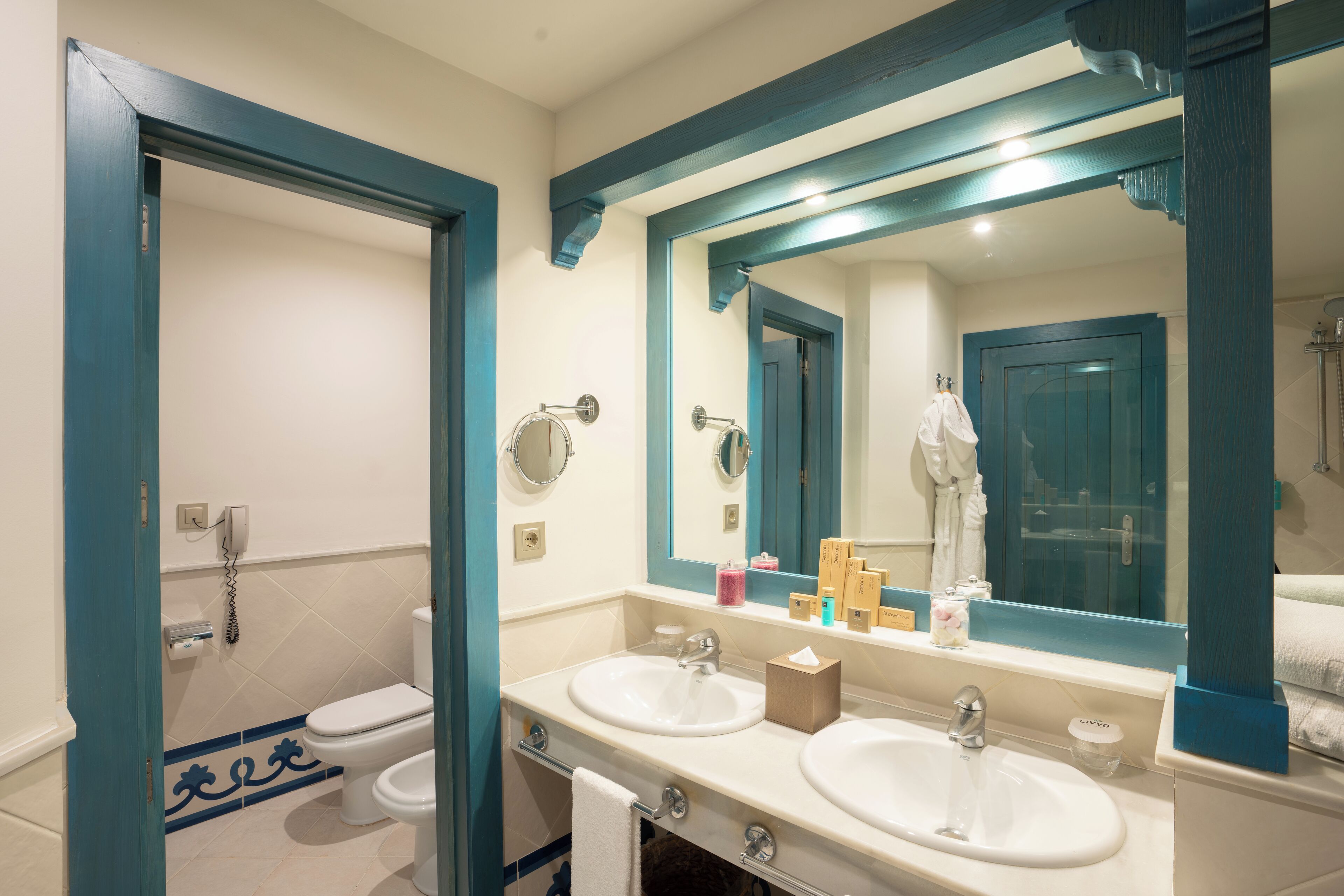 Une salle de bain avec deux lavabos, des toilettes et un miroir.