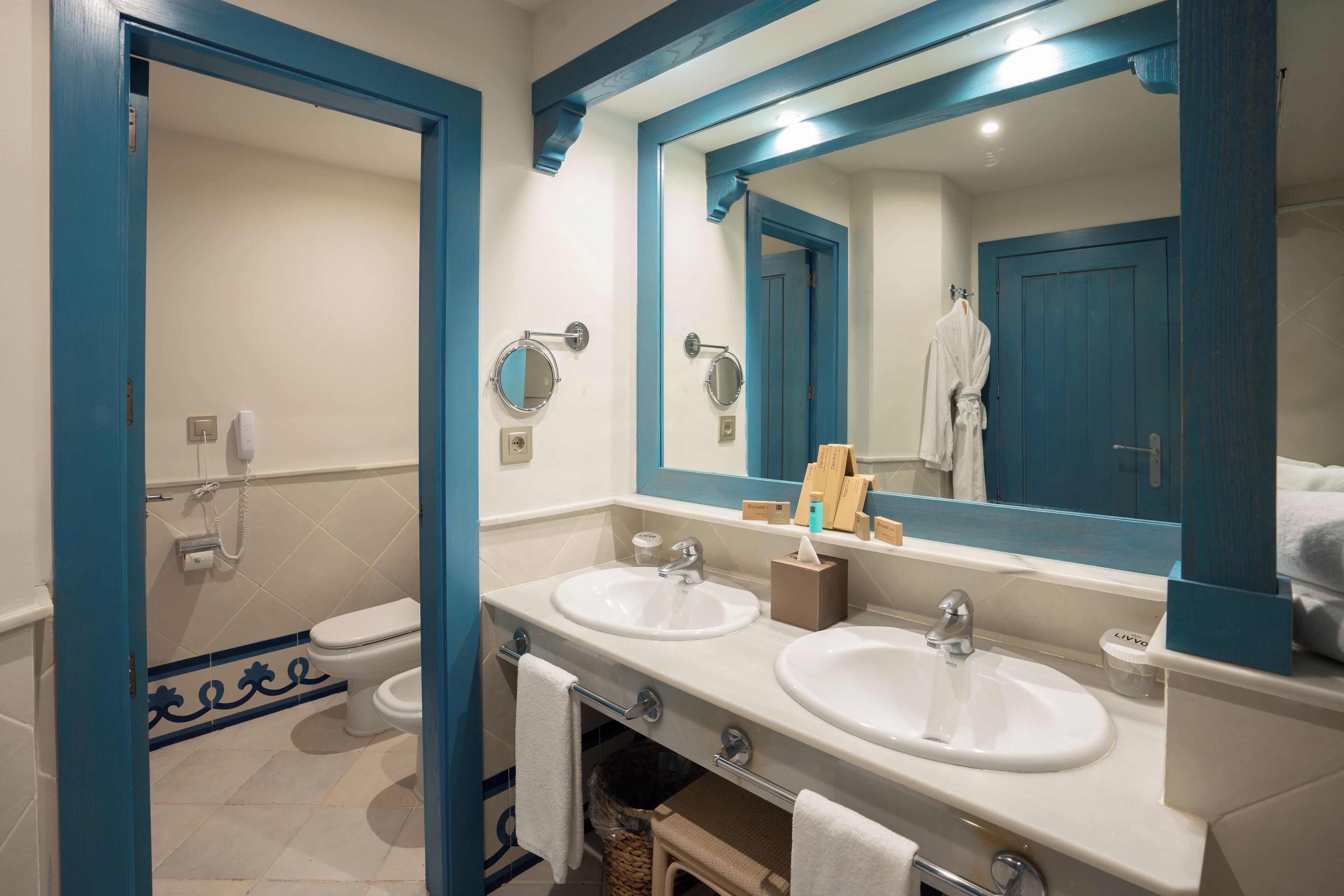 A bathroom with two sinks, a toilet, a mirror, and a towel rack.