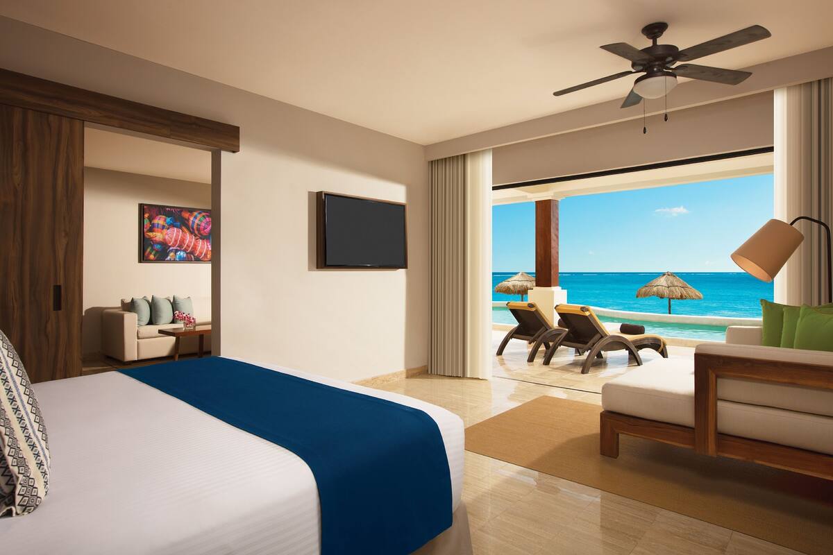 Een hotelkamer met een bed, een televisie, een bureau, een stoel en uitzicht op de oceaan.