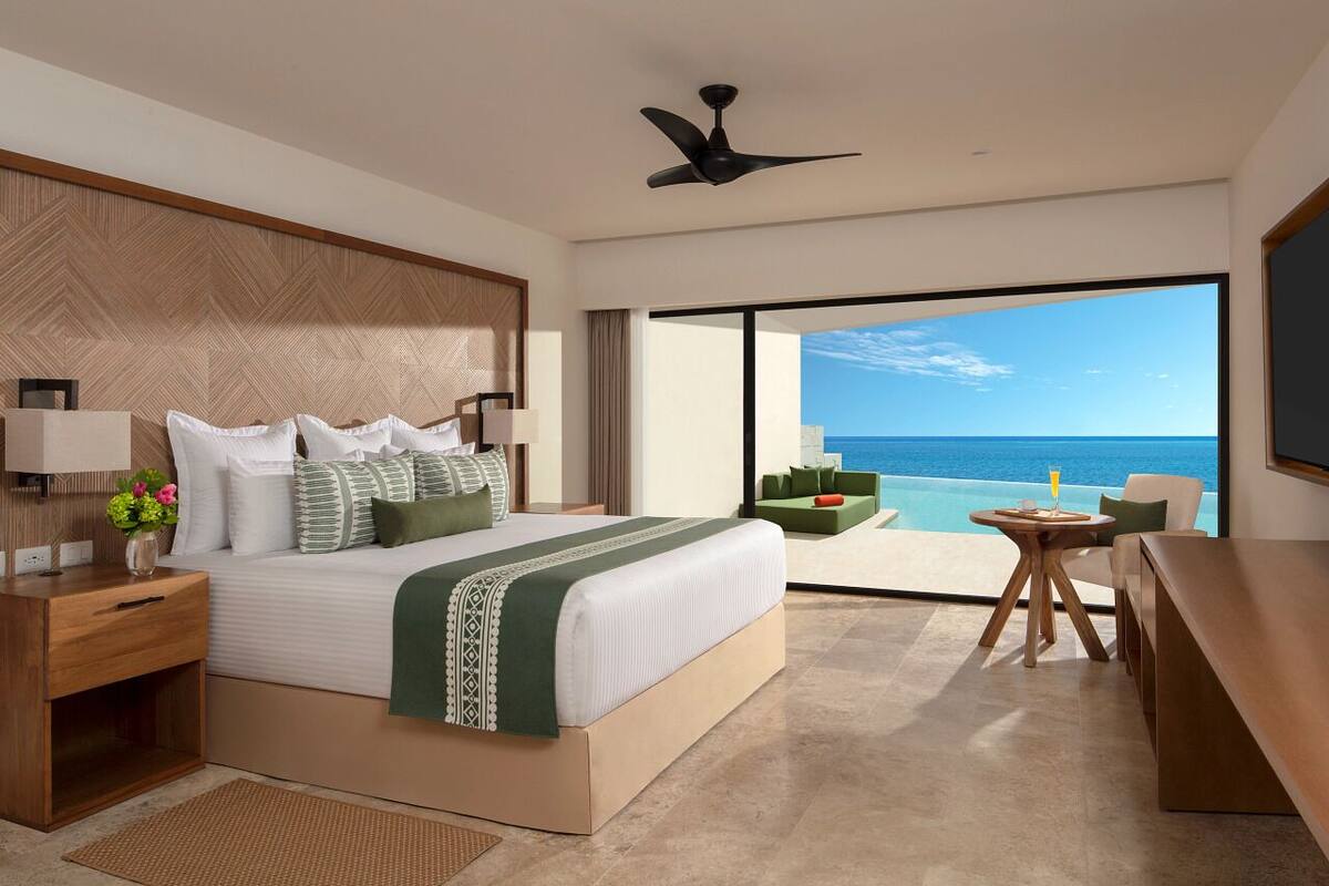 Een moderne hotelkamer met een groot bed, een bureau en uitzicht op de oceaan.