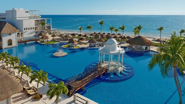 Ein Resort mit großem Pool, Palmen und Blick auf den Strand.