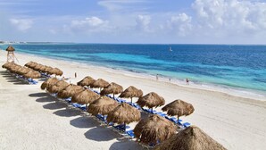 Ein Strand mit Reetsonnenstühlen und blauen Liegestühlen.