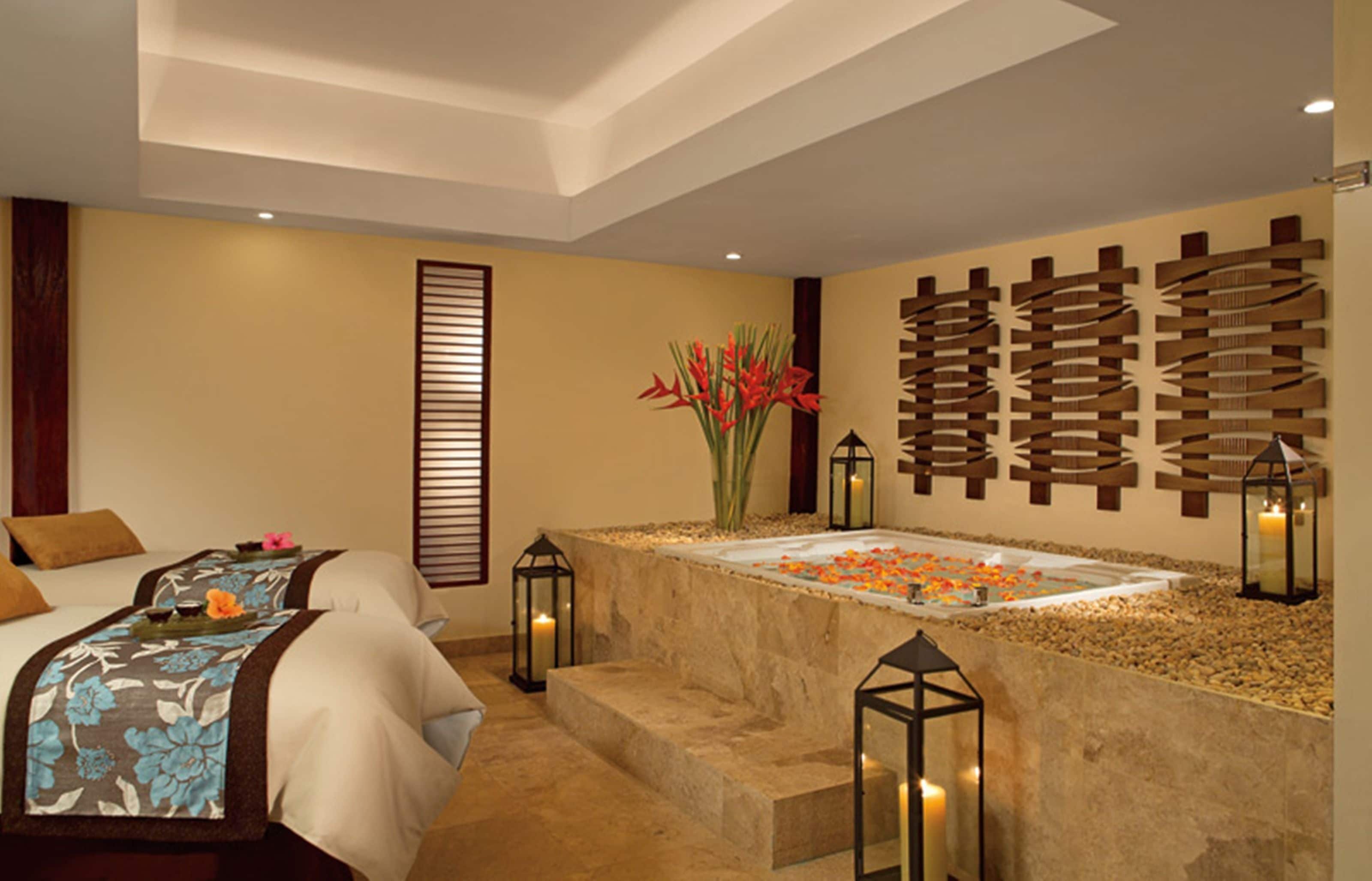 A spa room with a massage table, a decorative wall, and a small water feature.