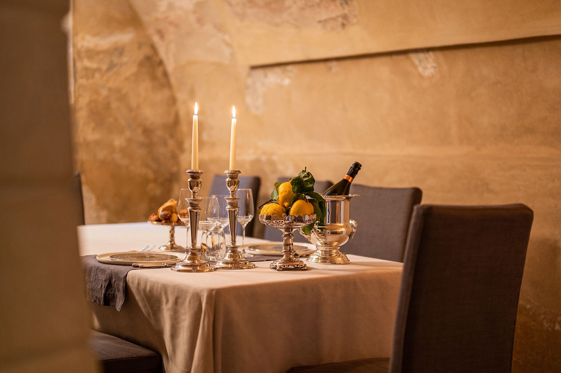 A table set with candles, a bottle of champagne, and a fruit arrangement.