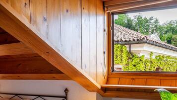 Une chambre à coucher avec un lit, une table de chevet, une lampe et une vue sur une maison par la fenêtre.