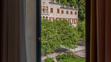 A view through a window of a building with a garden and a large structure in the background.