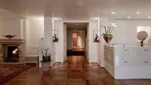 A modern interior with a wooden floor, a fireplace, and a hallway leading to another room. - Albergo Al Sole (Asolo)