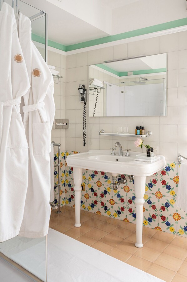 Un baño con lavamanos blanco, un espejo y una ducha.