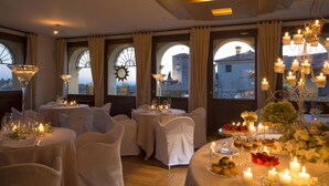 A dining area with round tables set for a meal, candles, and a chandelier. - Albergo Al Sole (Asolo)