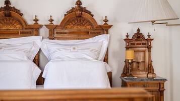 A neatly made bed with white linens and a wooden headboard with intricate carvings.