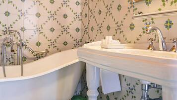 Un baño con bañera independiente, lavamanos e inodoro.