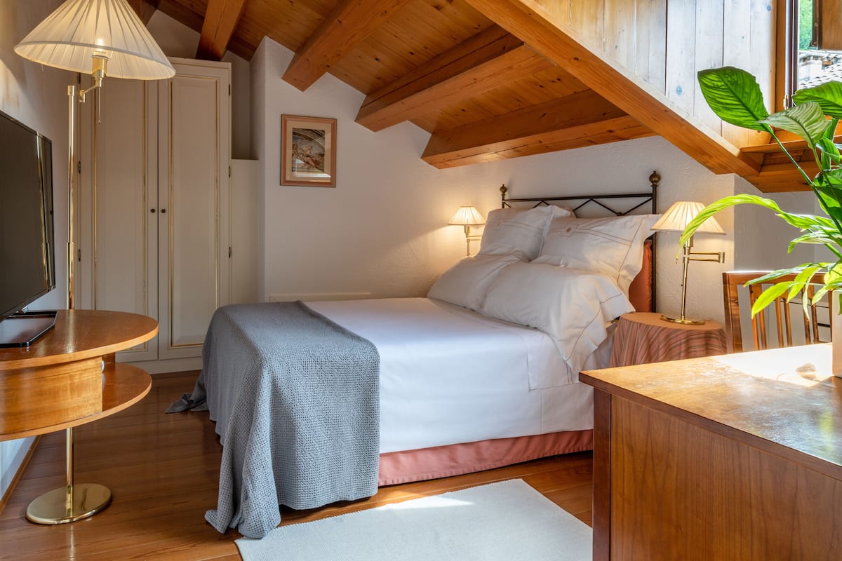 Un dormitorio con cama, lámparas de noche, un escritorio y una planta.