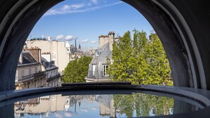 Vista a través de una ventana con el reflejo de edificios y árboles.