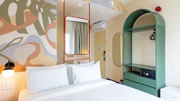 Camera d'albergo con un letto, un armadio, uno specchio e una parete decorata con arte astratta.