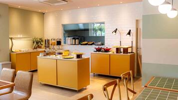 A modern kitchen with a central island, built-in appliances, and a dining area with chairs and a table.