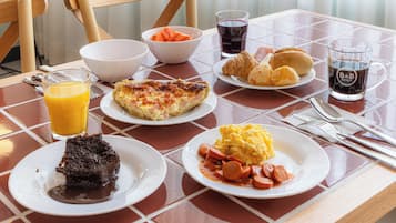Una mesa de desayuno con platos de comida, un vaso de jugo de naranja y una taza de café.