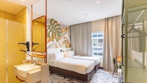 Una habitación de hotel con una cama grande, un baño con lavamanos y vistas a la ciudad.