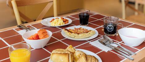 Una mesa de desayuno con platos de comida, un vaso de jugo de naranja y un vaso de café.