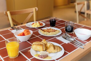 A breakfast table with plates of food, a glass of orange juice, and a glass of coffee.