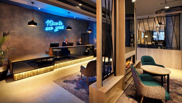 A modern hotel lobby with a reception desk, seating area, and a neon sign. - Leonardo Hotel London Croydon (Croydon)