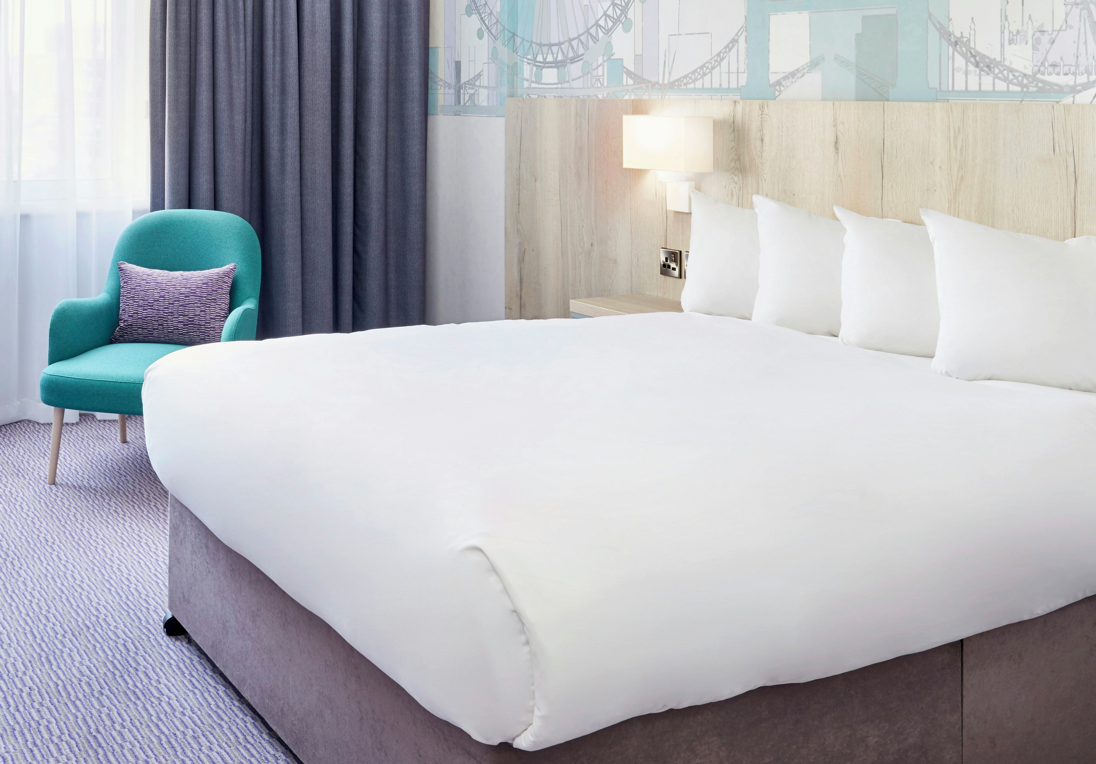 Une chambre d’hôtel avec un grand lit, une chaise, une lampe et un mur orné d’un motif décoratif.