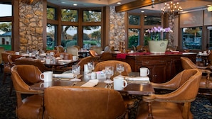A dining area with tables set for service, stone walls, and large windows with a view of the outdoors. - Arnold Palmer's Bay Hill Club & Lodge (Orlando)