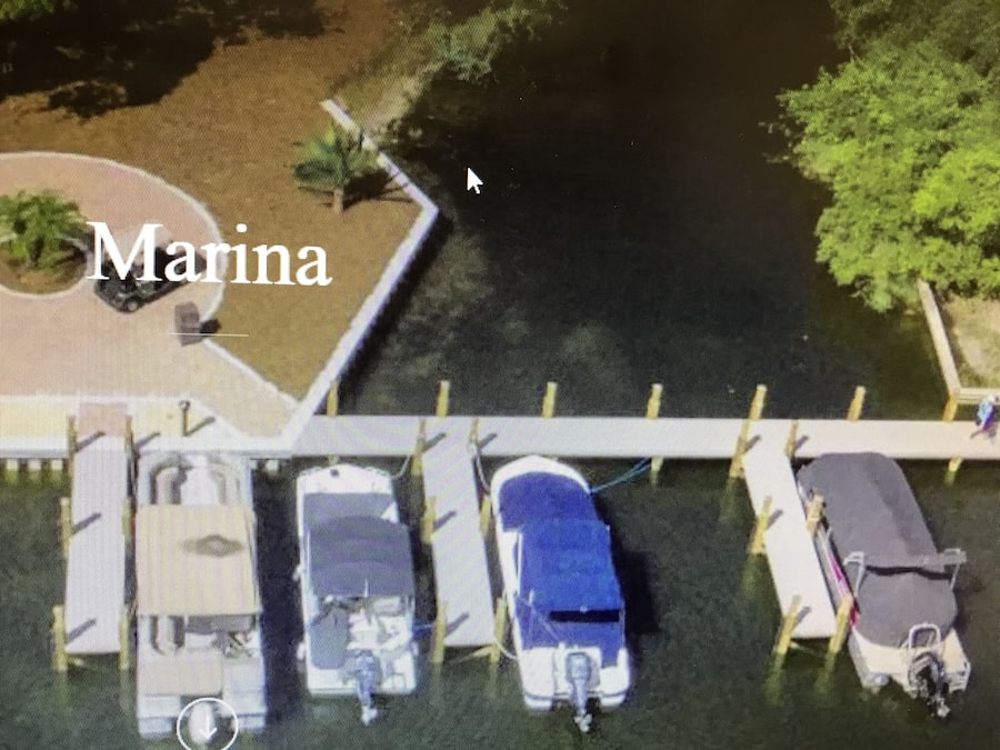 Un puerto deportivo con barcos amarrados, un puente peatonal y un aparcamiento.