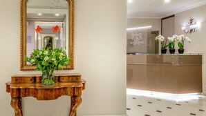 A reception area with a wooden console table, a large mirror, and a vase of flowers.