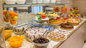 A buffet with various food items, including fruits, pastries, and desserts.