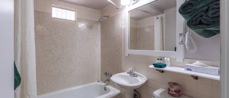 Un baño con bañera, lavamanos, inodoro y espejo.