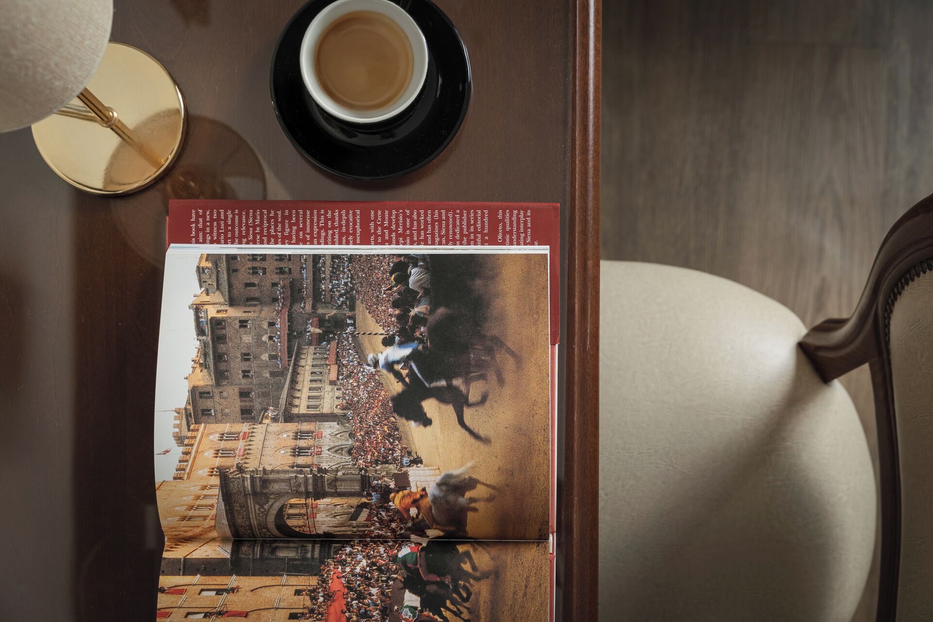 Een boek met een historische illustratie, een kop koffie en een stoel.