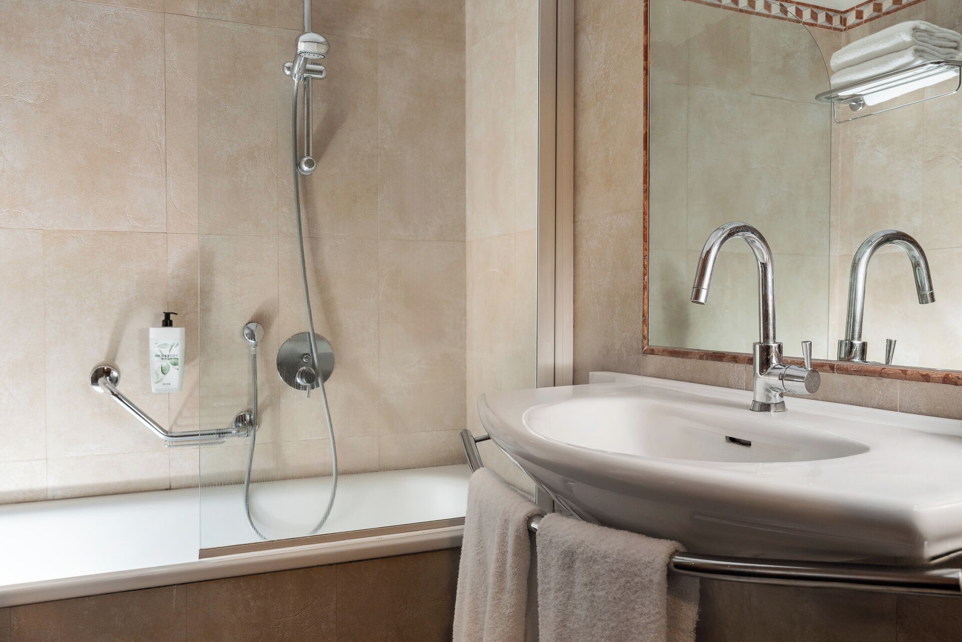 A bathroom with a bathtub, a sink, a mirror, and a showerhead.