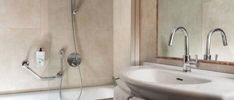 A bathroom with a bathtub, a sink, a mirror, and a showerhead.