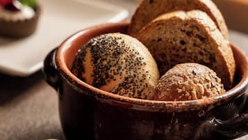 Una ciotola di pane con semi, un piccolo piatto con un oggetto rotondo e uno sfondo sfocato.