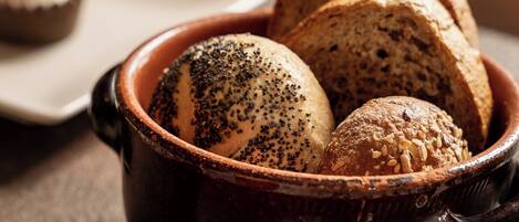 A bowl of bread with seeds, a small plate with a round item, and a blurred background.