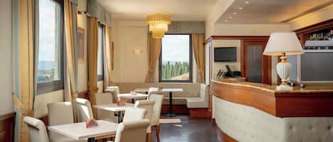 A hotel lobby with seating, a reception desk, and large windows offering a view.