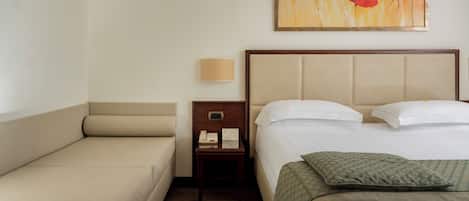 Une chambre d’hôtel avec un lit, un canapé, une table de chevet, une lampe et un tableau au mur.