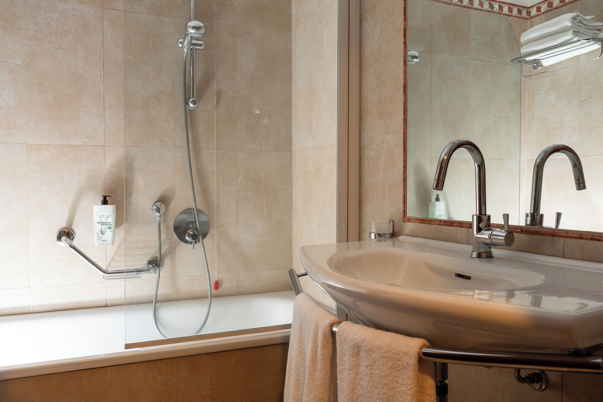 Une salle de bain équipée d’une baignoire, d’un lavabo, d’un miroir et d’une pomme de douche.