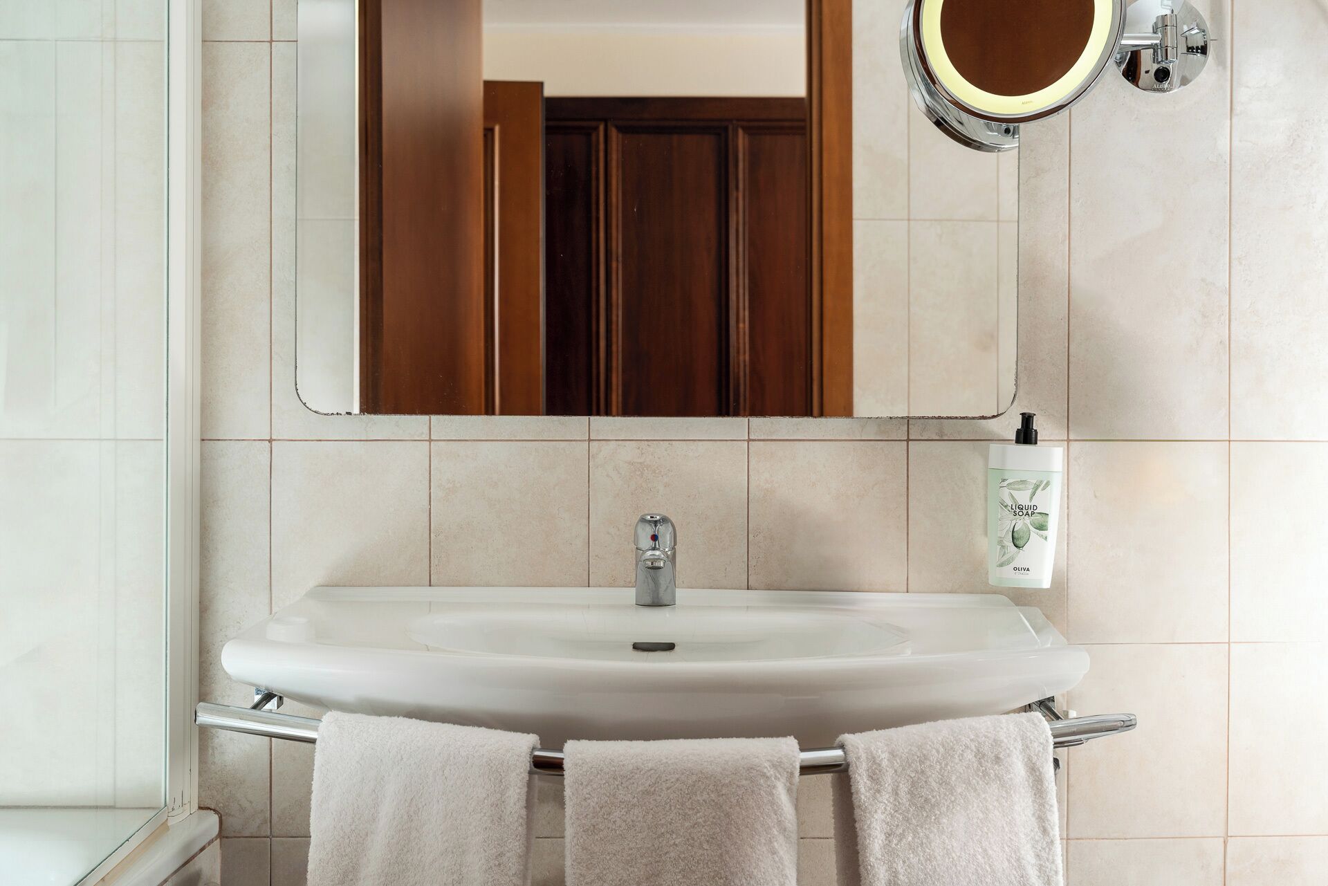 A bathroom with a white sink, a mirror, and a towel rack.