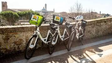 Due biciclette parcheggiate su un muro di pietra, con una città sullo sfondo.