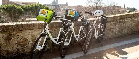 Two bicycles parked on a stone wall with a cityscape in the background.