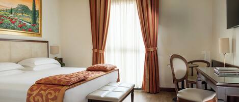 A hotel room with a bed, a desk, a chair, and a painting on the wall.