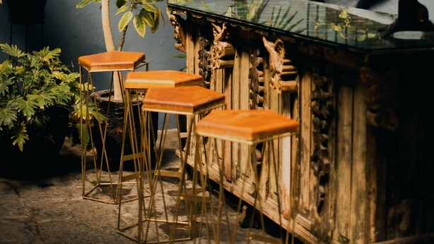 Una zona de bar con taburetes de madera y una barra con encimera de vidrio.
