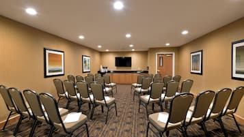 Una sala conferenze con un lungo tavolo e sedie, un televisore a schermo piatto e quadri appesi alle pareti.