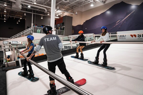 Uma instalação interna para snowboard com vários praticantes a treinar em corrimãos.