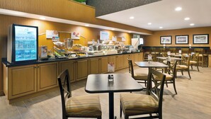 Un espace de restauration d’hôtel comprenant un buffet, des meubles de rangement en bois et des tables avec des chaises.