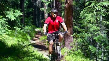 A mountain biker on a dirt trail surrounded by dense forest.
