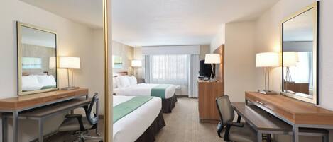 Une chambre d’hôtel avec deux lits, un bureau, une chaise, une télévision et un grand miroir.