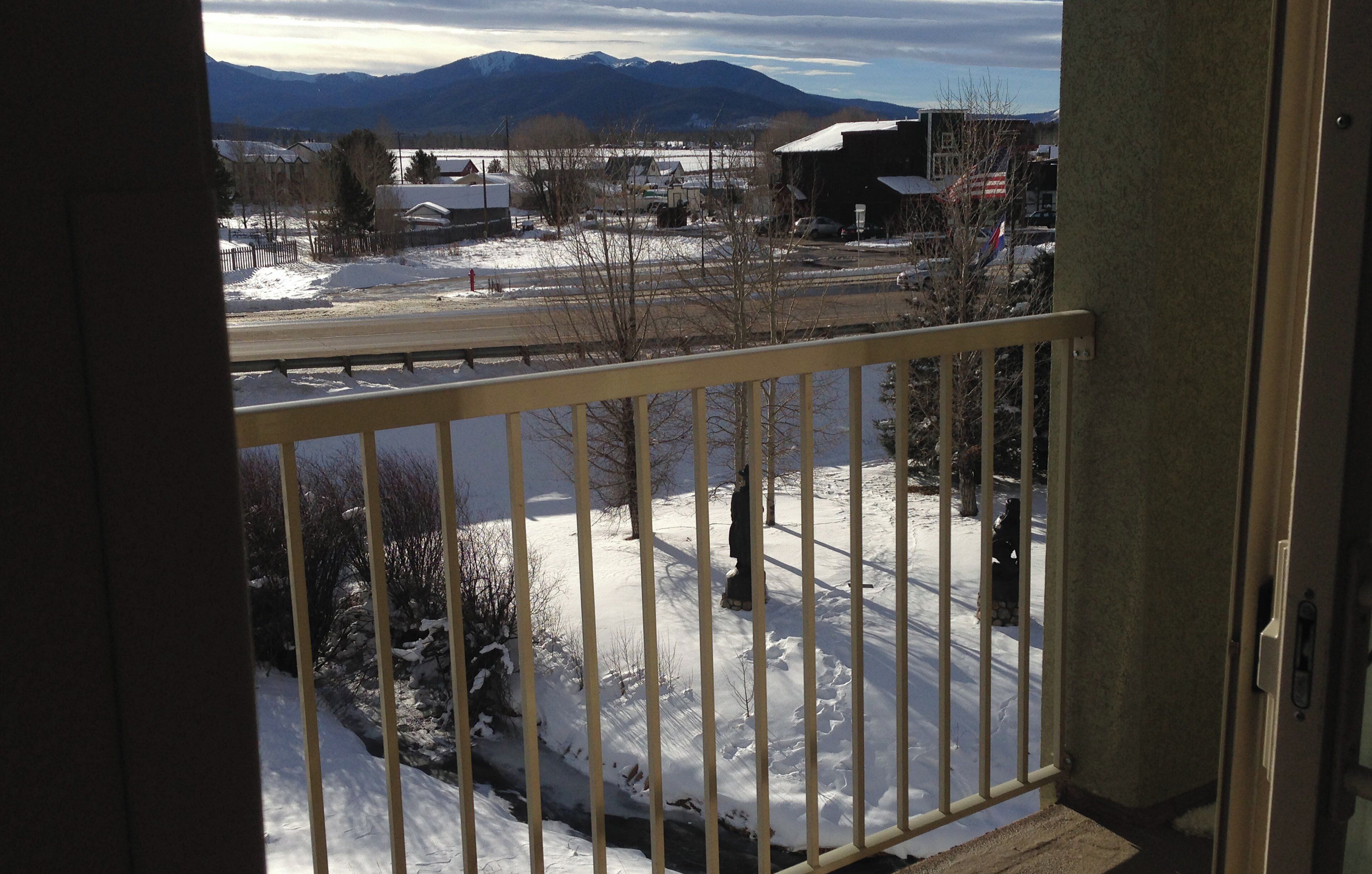 A balcony with a view of a snowy landscape, a road, and distant mountains.