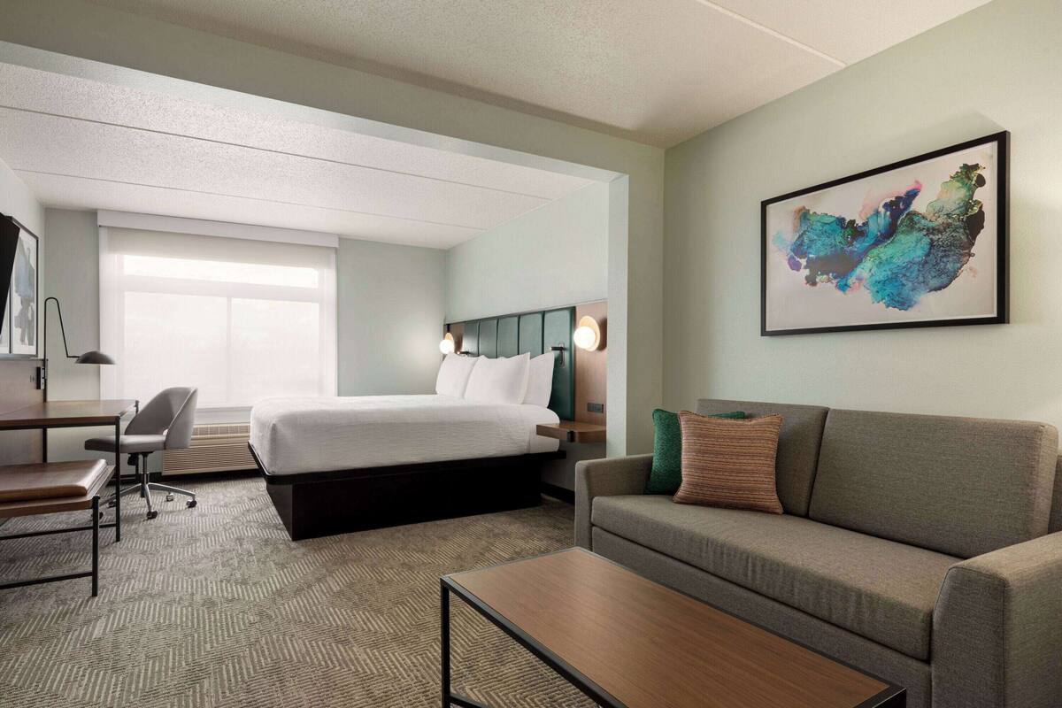 Una habitación de hotel con una cama, un sofá, un escritorio y una silla.